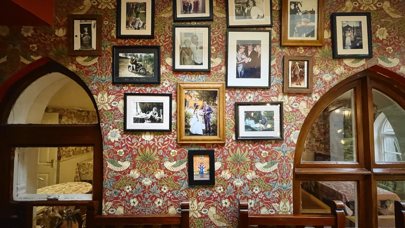 A wall at Langar Hall filled with framed family photographs