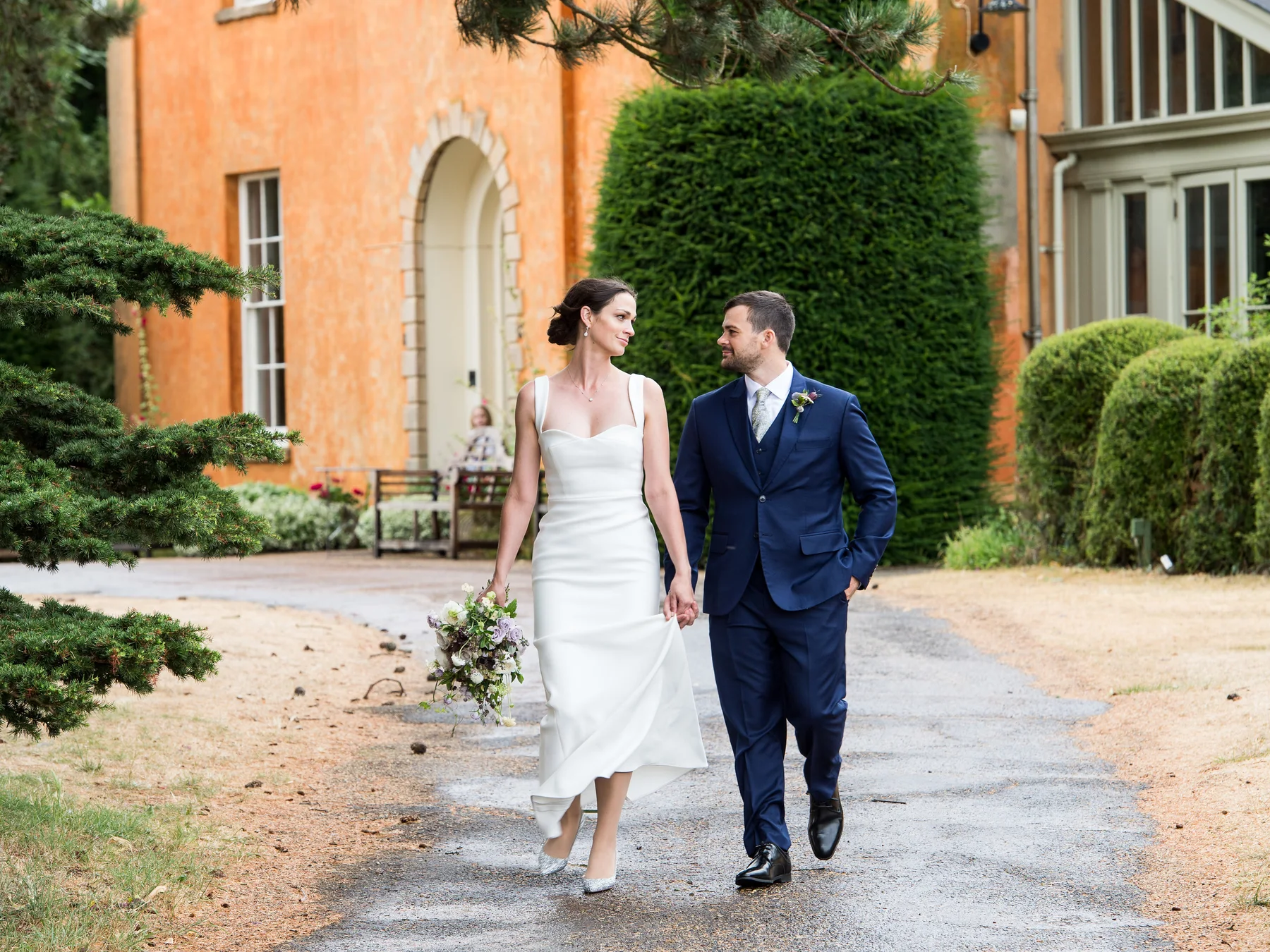 A newly married couple walking through the grounds at Langar Hall